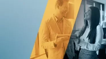 Duas pessoas sorrindo e conversando em um escritório.