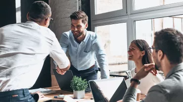 pessoas em sala de reunião, homem apertando mãos;