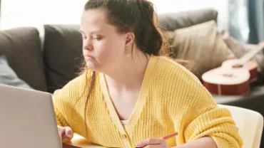 Mulher com sindrome de down trabalhando em seu notebook na sala de sua casa