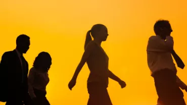 Pessoas caminhando contra o pôr do sol.
