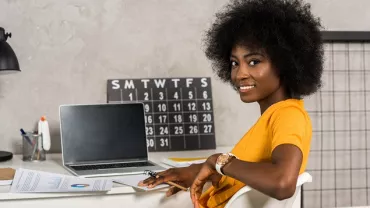mulher negra sorrindo sentada em frente a um computador