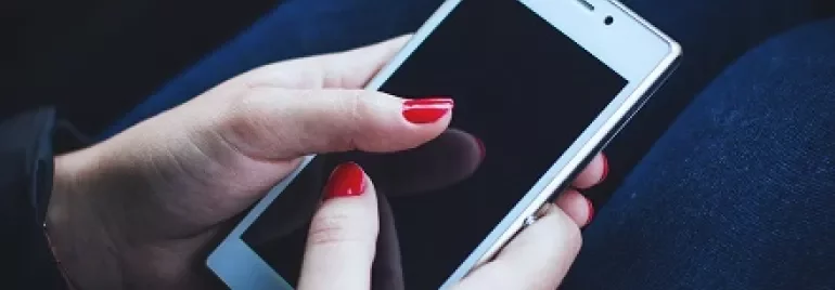 Pessoa segurando um smartphone branco com tela preta.