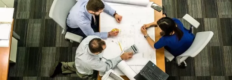 Reunião de pessoas analisando projetos em escritório.